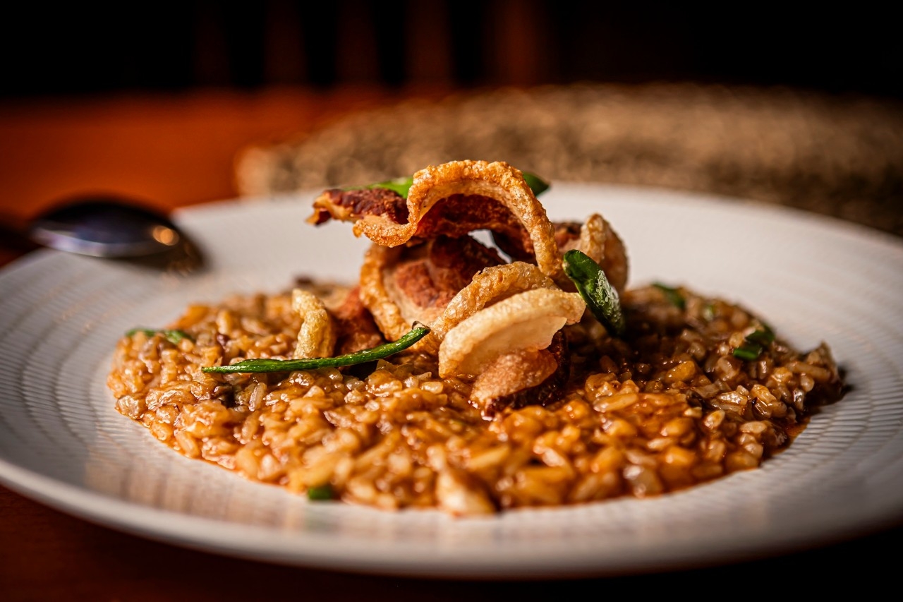 Arroz meloso con manitas, tirabeques y torrezno de Soria.