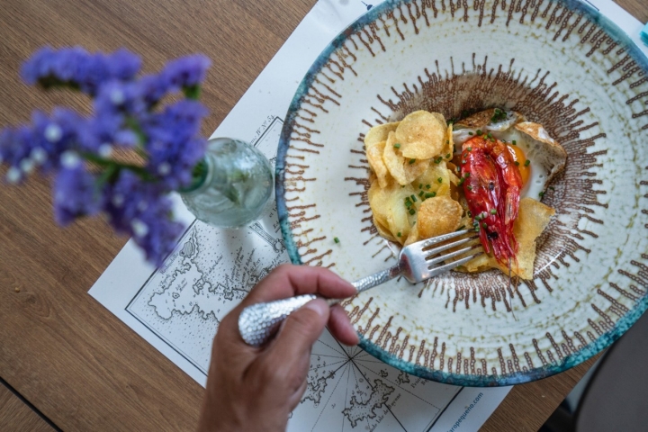 Carabineros al ajillo con huevo frito y patatas chip.