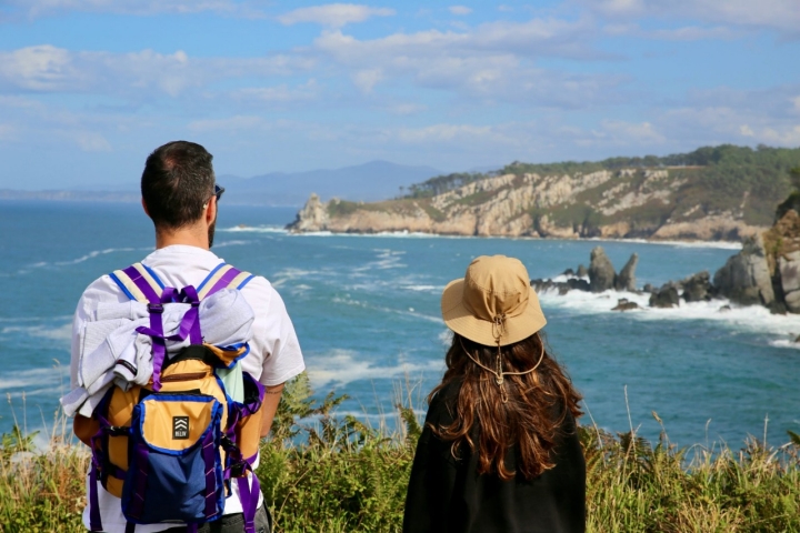 Dos senderistas se asoman a un mirador de la Senda Costa Naviega